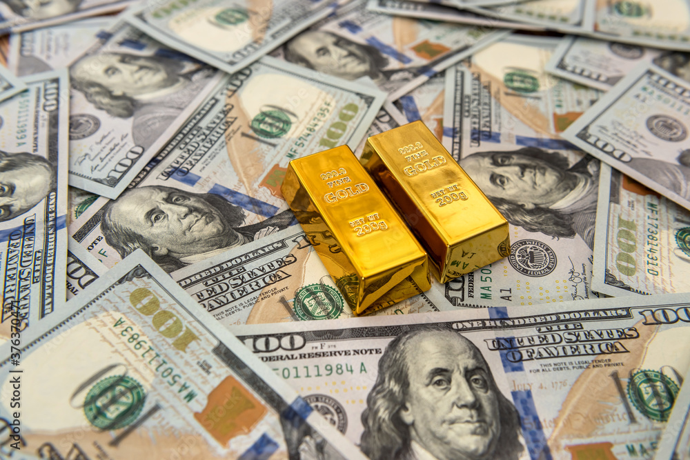 Expensive gold bar lying on dollar bills Expensive gold bar lying on dollar bills