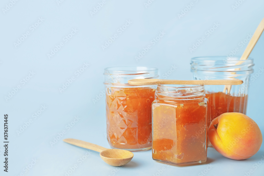 Jars of tasty apricot jam on color background Jars of tasty apricot jam on color background