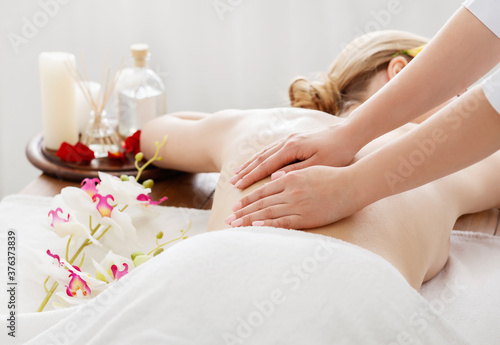 Spa day. Girl receives massage on table with flowers and oil