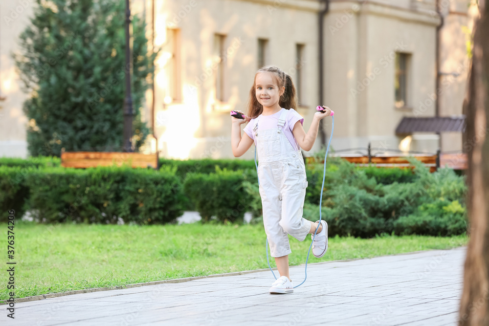 Cute little girl jumping rope outdoors