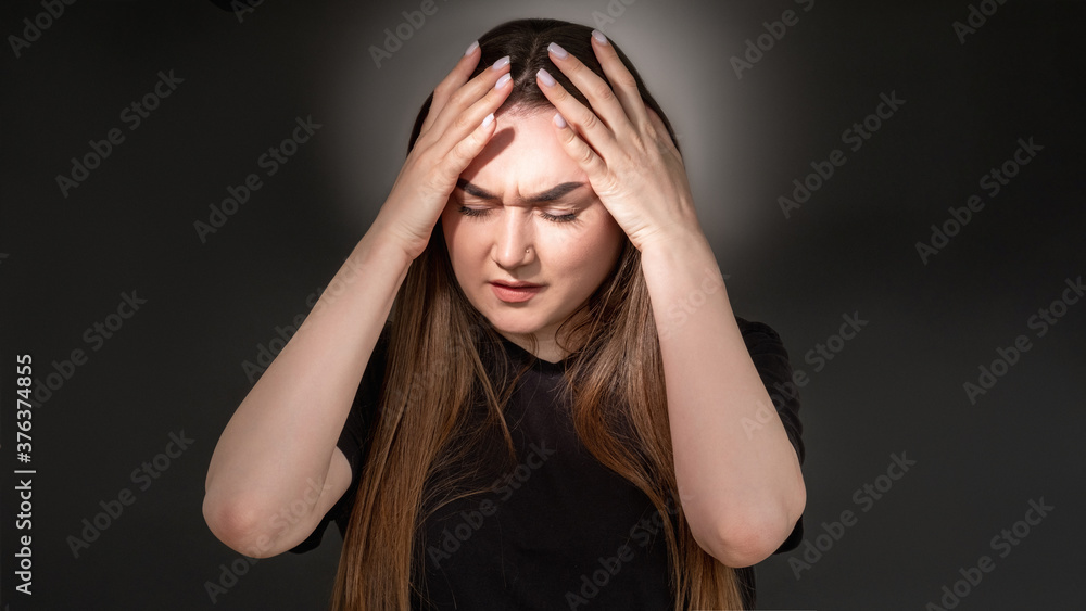 Suffering woman. Social pressure. Portrait of frustrated stressed overweight lady in black t-shirt touching head isolated on dark illuminated copy space background. Mental disorder. Anxiety crisis. Suffering woman. Social pressure. Portrait of frustrated stressed overweight lady in black t-shirt touching head isolated on dark illuminated copy space background. Mental disorder. Anxiety crisis.