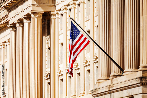 US flag over classical government building with columns in Washington, DC
