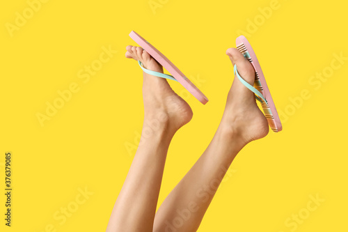 Legs of young woman in flip-flops on color background photo