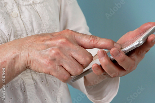 An elderly person using a smartphone. Close-up of an elderly person who is worried about how to use a smartphone.                                                                                               