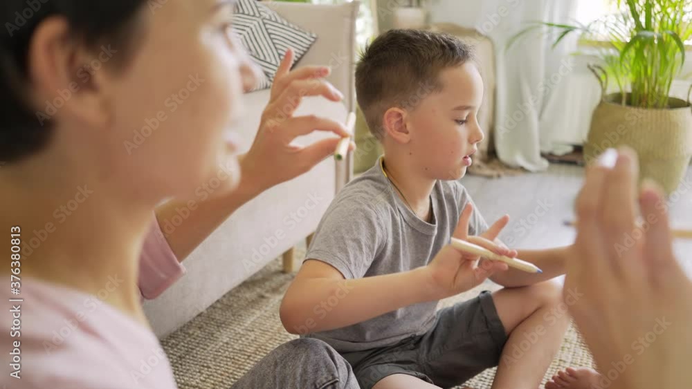 positive young mother with little son and daughter does developing exercises for fingers with wooden pencils in light living room close view positive young mother with little son and daughter does developing exercises for fingers with wooden pencils in light living room close view