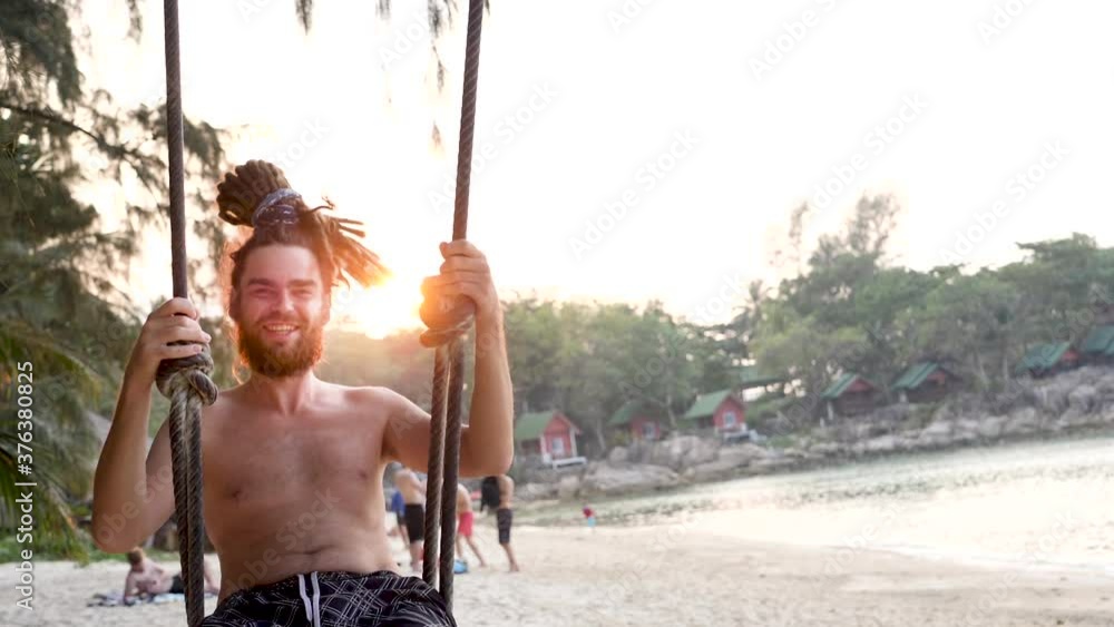 Emotion smiles man swing beach on seashore. Holiday or vacation in tropical beach. Sunset background Emotion smiles man swing beach on seashore. Holiday or vacation in tropical beach. Sunset background