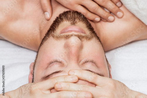 Top view of man receiving relaxing head massage by hands of massage therapist