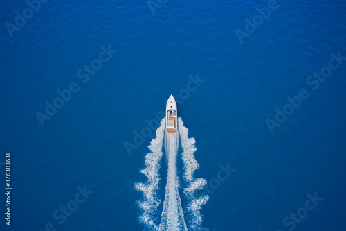 Top view of a white boat sailing in the blue sea. luxury motor boat. Aerial view of a boat in motion on blue water. Drone view of a boat sailing at high speed. © Berg