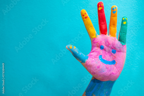 Paint the water on the hand.. Smiley on hand against blue background.