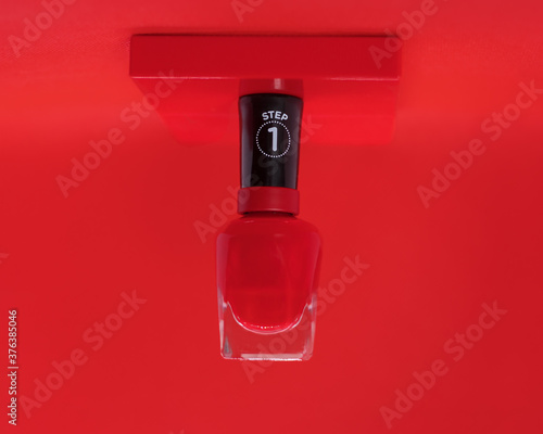 Juicy red nail Polish on red background hovers hanging levitation. The concept of hand care, advertising manicure salon, manufacturer of nail polishes, beautiful nails. Close-up photo. Sign Step 1 © Татьяна Волкова