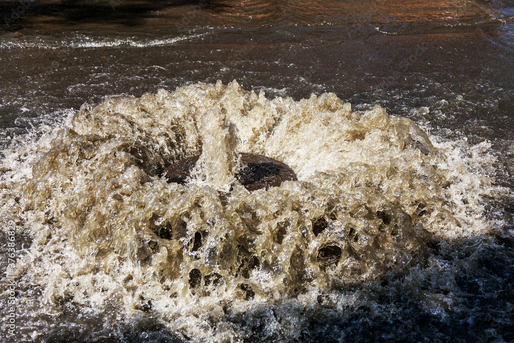 Water flows out of drainage hatch. Drainage fountain of sewage