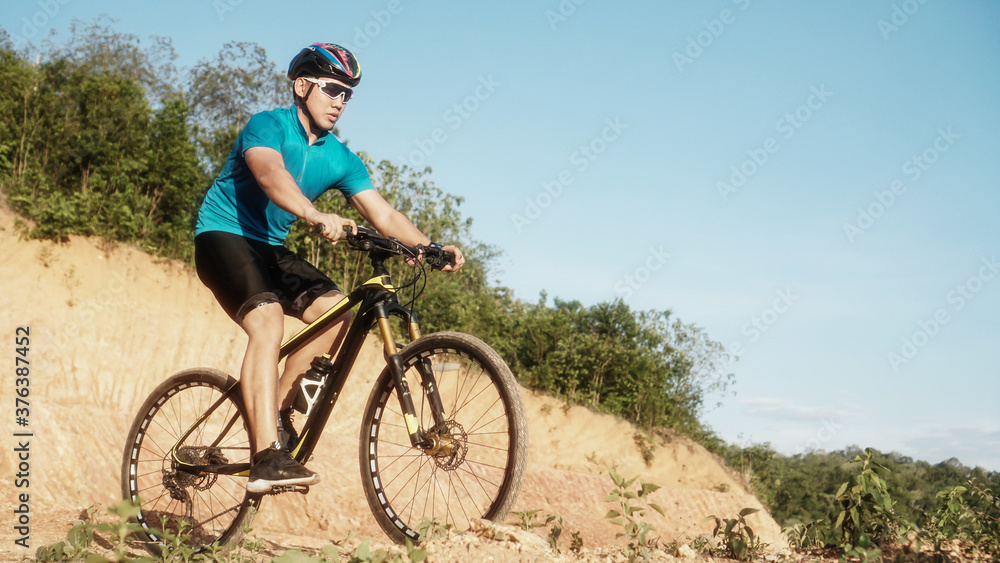 Man is riding bicycle, on the background of rocky trail in mountain area bike on trail at evening.mountain bike racing.healthy lifestyle.xtreme sports.vintage tone.selective focus. Man is riding bicycle, on the background of rocky trail in mountain area bike on trail at evening.mountain bike racing.healthy lifestyle.xtreme sports.vintage tone.selective focus.