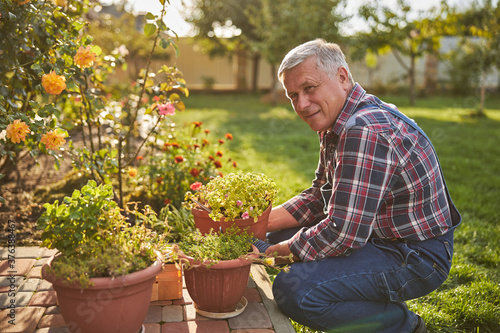 Enthusiastic gardener posing beside his potted plants