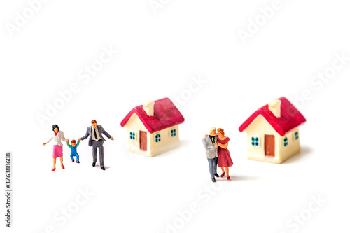 miniature couple with tiny home and piggy bank isolated on white background.