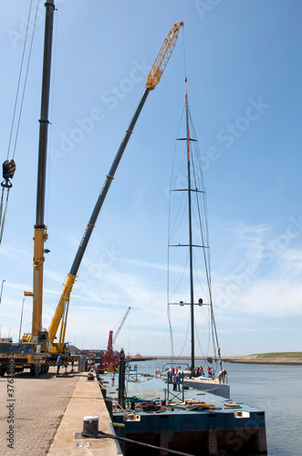 Placing the mast on a superyacht. Cranes. Harbor. Ship building industry.