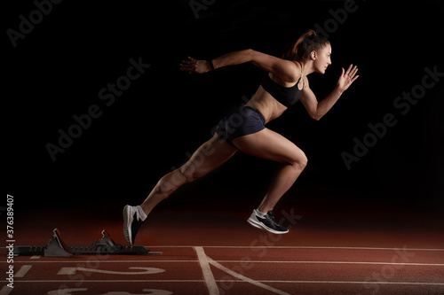Woman Sprinter in Mid Action Bursting From Blocks During Race