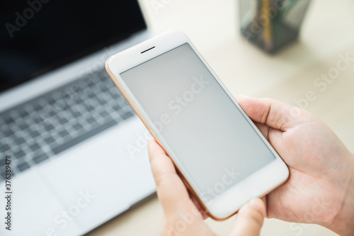 Woman hand holding smartphone and touching blank screen. Mockup of advertisement.