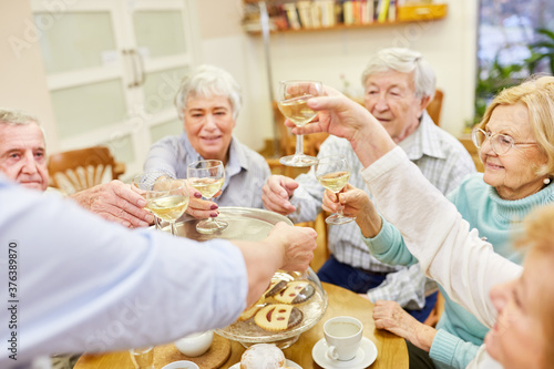 Group of seniors celebrates birthday with white wine