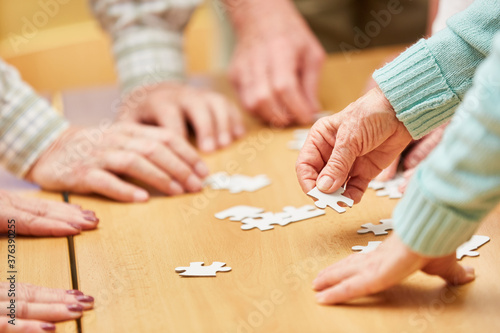 Hand of a senior citizen holds a piece of the puzzle