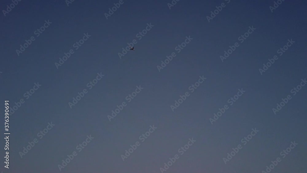 Distant commercial plane in twilight sky soaring high through air, slow motion Distant commercial plane in twilight sky soaring high through air, slow motion