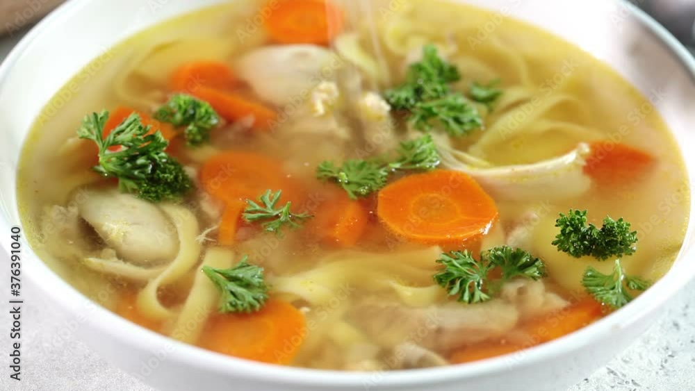 Homemade chicken soup with noodles and vegetables in white bowl, white background. Healthy warm comfortable food. Homemade chicken soup with noodles and vegetables in white bowl, white background. Healthy warm comfortable food.