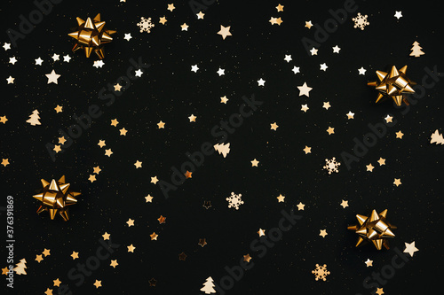 Festive dark background with many golden Christmas and New Year decorations and stars.