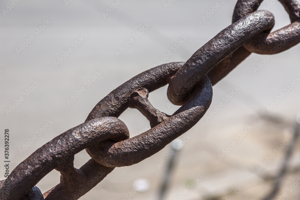 The old rusty metal chain of the anchor of the ship. Giant heavy steel chain leading from land to sea. Yellow mooring line of cargo ship. Ancient rusty Marine anchor chain The old rusty metal chain of the anchor of the ship. Giant heavy steel chain leading from land to sea. Yellow mooring line of cargo ship. Ancient rusty Marine anchor chain