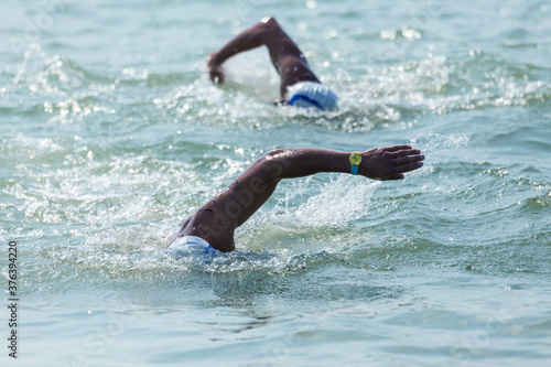 Swimmer swims in sea. Athlete triathlete swimmer drains from water. Professional athlete in triathletes trains for an ironman. The sportsman beautifully floats in blue sea water at competitions