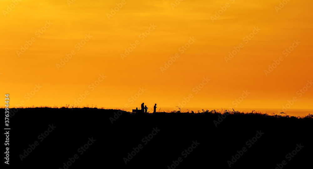 Family silhouette having fun on the beach at the sunset time. Concept of friendly family and of summer vacation.