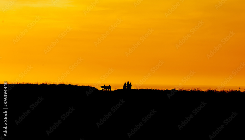 Family silhouette having fun on the beach at the sunset time. Concept of friendly family and of summer vacation.