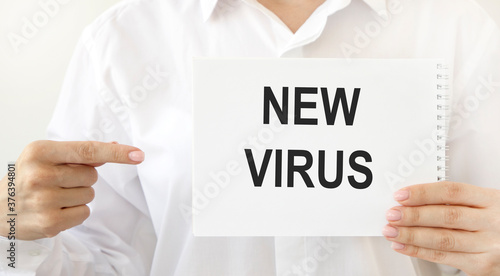 On a tablet with a fixed sheet of paper inscription NEW VIRUS, next to an electronic thermometer and tablets.