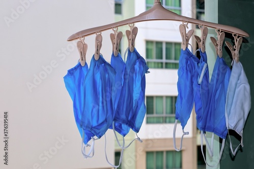 Fabric mask hanging by pegs at balcony of residential, Dry clothes in the sun for disinfect virus bacteria, prevent from epidemic of disease during the corona virus outbreak situation.