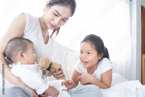 happy loving family. Love, trust and tenderness concept. Mother and child on a white bed. Parent and little kid relaxing at home. Mother and her daughters children girls playing and hugging.