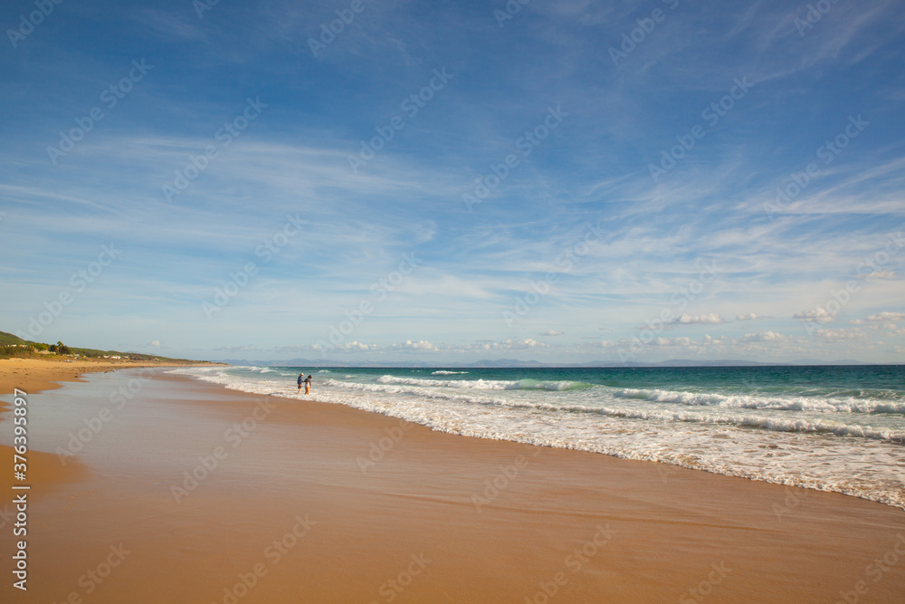 Two people on the shore of the long beach of Zahara de los Atunes in the Atlantic Ocean, Cadiz, Spain