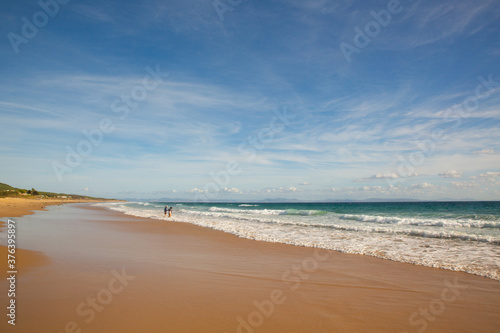Two people on the shore of the long beach of Zahara de los Atunes in the Atlantic Ocean, Cadiz, Spain