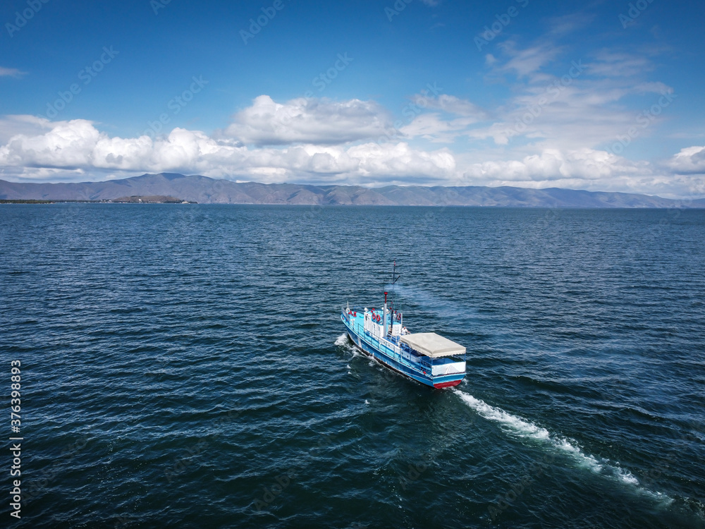 Naklejka premium Aerial view of a steamboat, A fishing ship in the middle of a lake with beautiful coastline behind