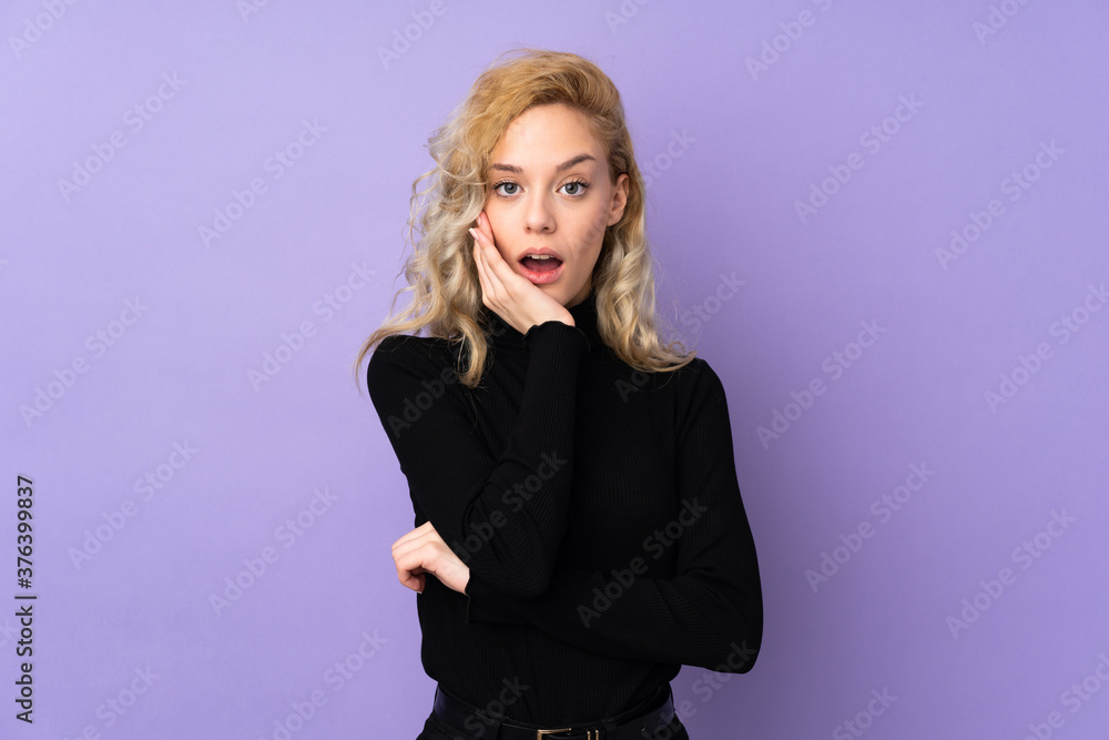 Young blonde woman isolated on purple background surprised and shocked while looking right Young blonde woman isolated on purple background surprised and shocked while looking right