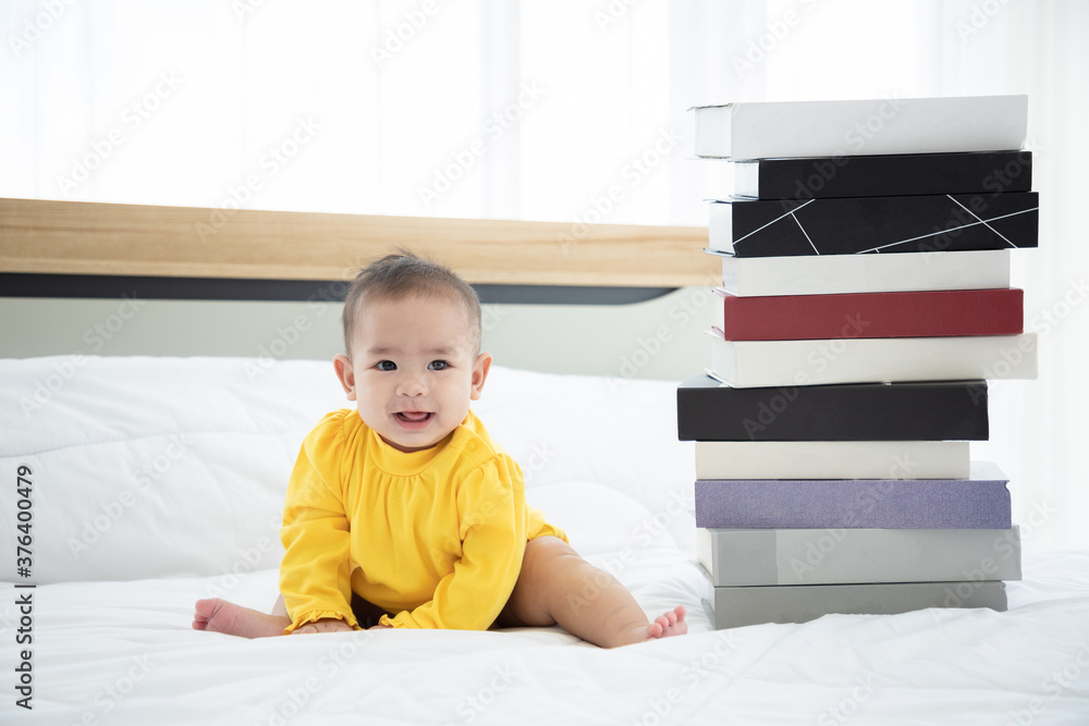 Happy excited infant baby girl crawling on the bed with books in the morning. Being a good child. Happy excited infant baby girl crawling on the bed with books in the morning. Being a good child.