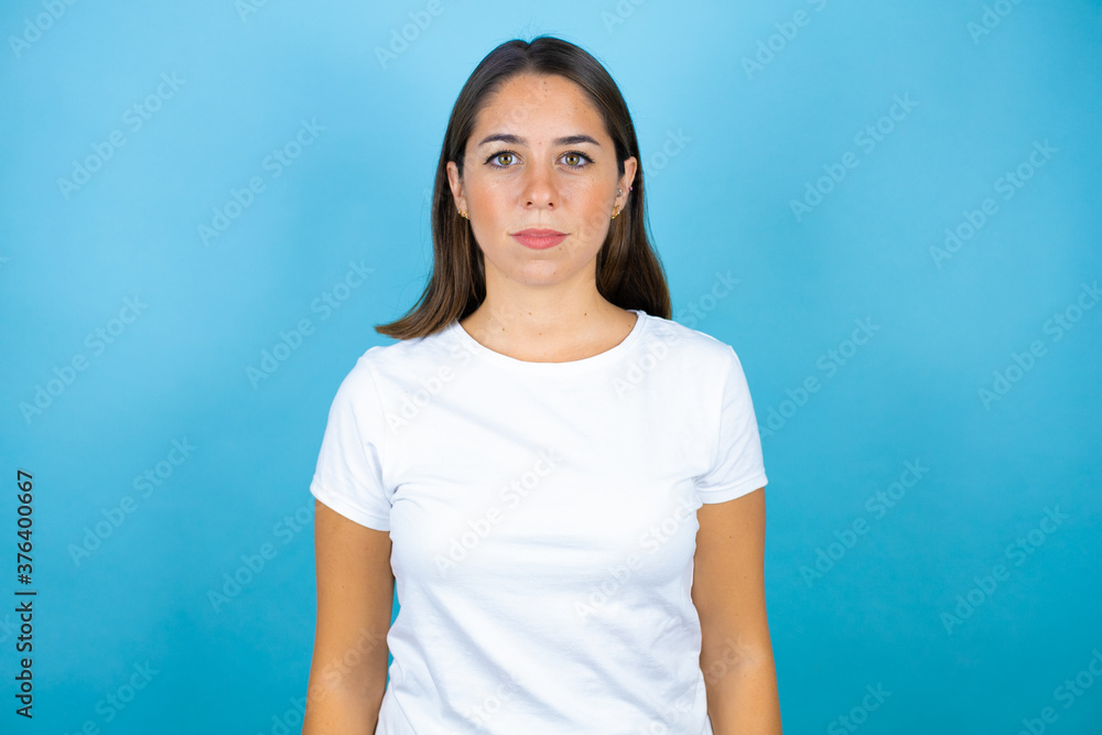 Young beautiful woman over isolated blue background serious looking at the camera Young beautiful woman over isolated blue background serious looking at the camera