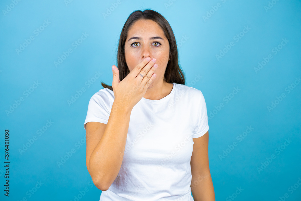 Young beautiful woman over isolated blue background surprised covering her mouth Young beautiful woman over isolated blue background surprised covering her mouth