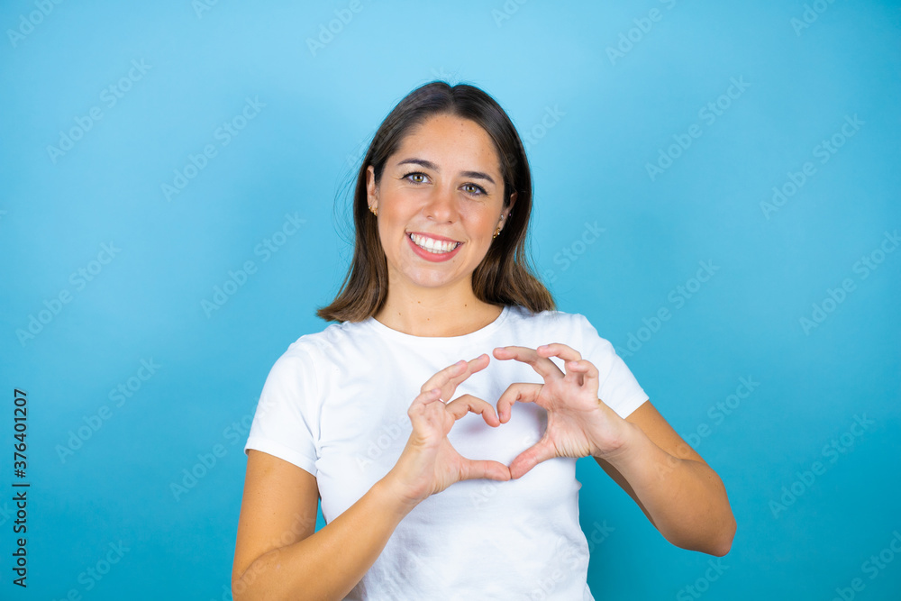 Young beautiful woman over isolated blue background smiling in love showing heart symbol and shape with hands Young beautiful woman over isolated blue background smiling in love showing heart symbol and shape with hands