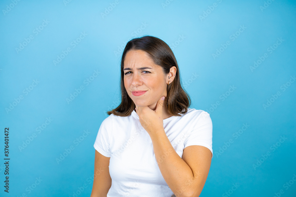 Young beautiful woman over isolated blue background touching painful neck, sore throat for flu, clod and infection Young beautiful woman over isolated blue background touching painful neck, sore throat for flu, clod and infection