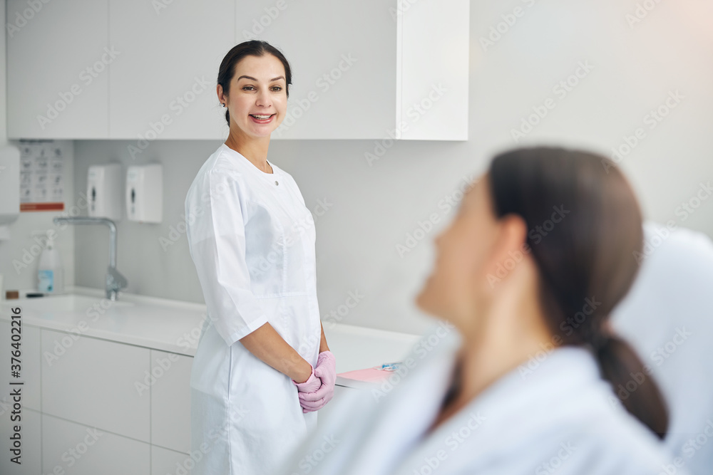 Cheerful middle-aged beautician looking at her client Cheerful middle-aged beautician looking at her client