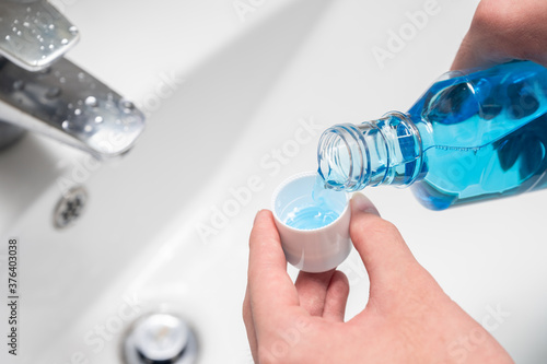 Hand of man Pouring Bottle Of Mouthwash Into Cap.