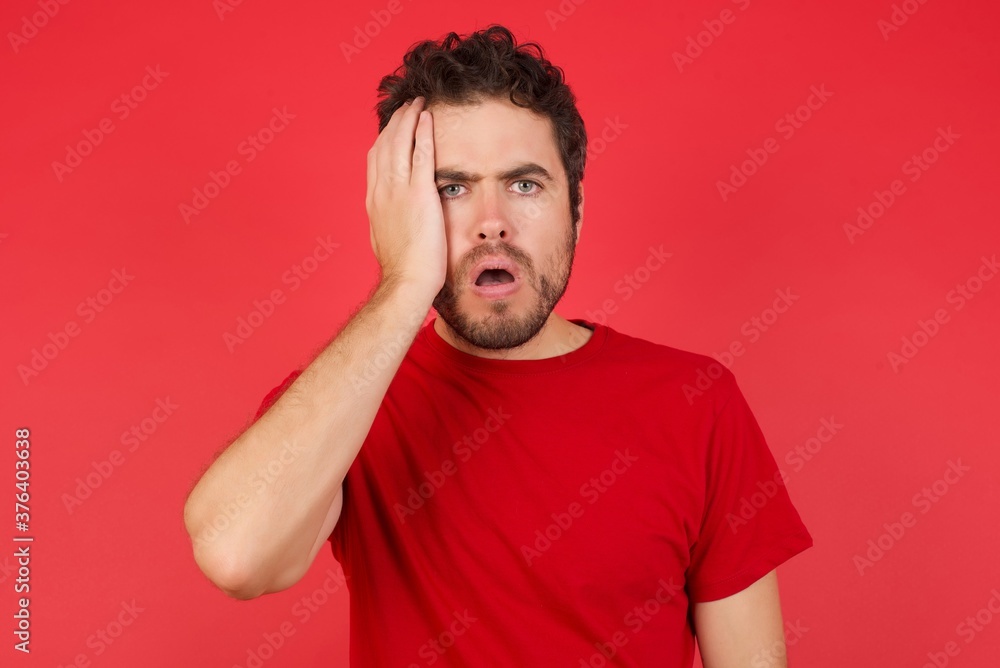 Embarrassed Young handsome caucasian man wearing t-shirt over isolated red background, with shocked expression, expresses great amazement, Puzzled man poses indoor Embarrassed Young handsome caucasian man wearing t-shirt over isolated red background, with shocked expression, expresses great amazement, Puzzled man poses indoor