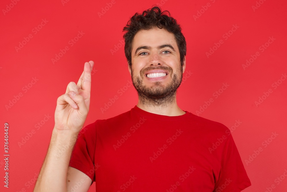 Young handsome caucasian man wearing t-shirt over isolated red background pointing up with fingers number ten in Chinese sign language Shi Young handsome caucasian man wearing t-shirt over isolated red background pointing up with fingers number ten in Chinese sign language Shi