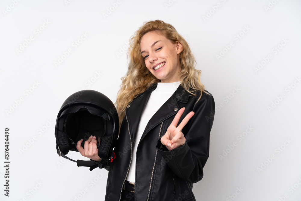 Young blonde woman with a motorcycle helmet isolated on white background smiling and showing victory sign Young blonde woman with a motorcycle helmet isolated on white background smiling and showing victory sign