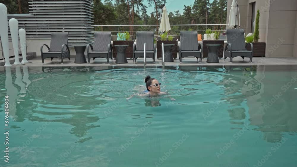 brunette young woman in sunglasses swimming in pool brunette young woman in sunglasses swimming in pool