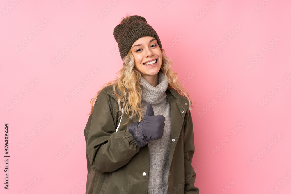 Young girl with winter hat isolated on pink background giving a thumbs up gesture Young girl with winter hat isolated on pink background giving a thumbs up gesture