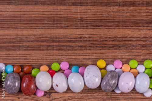 Colored eggs and colored chocolate tablets on exotic natural wood background